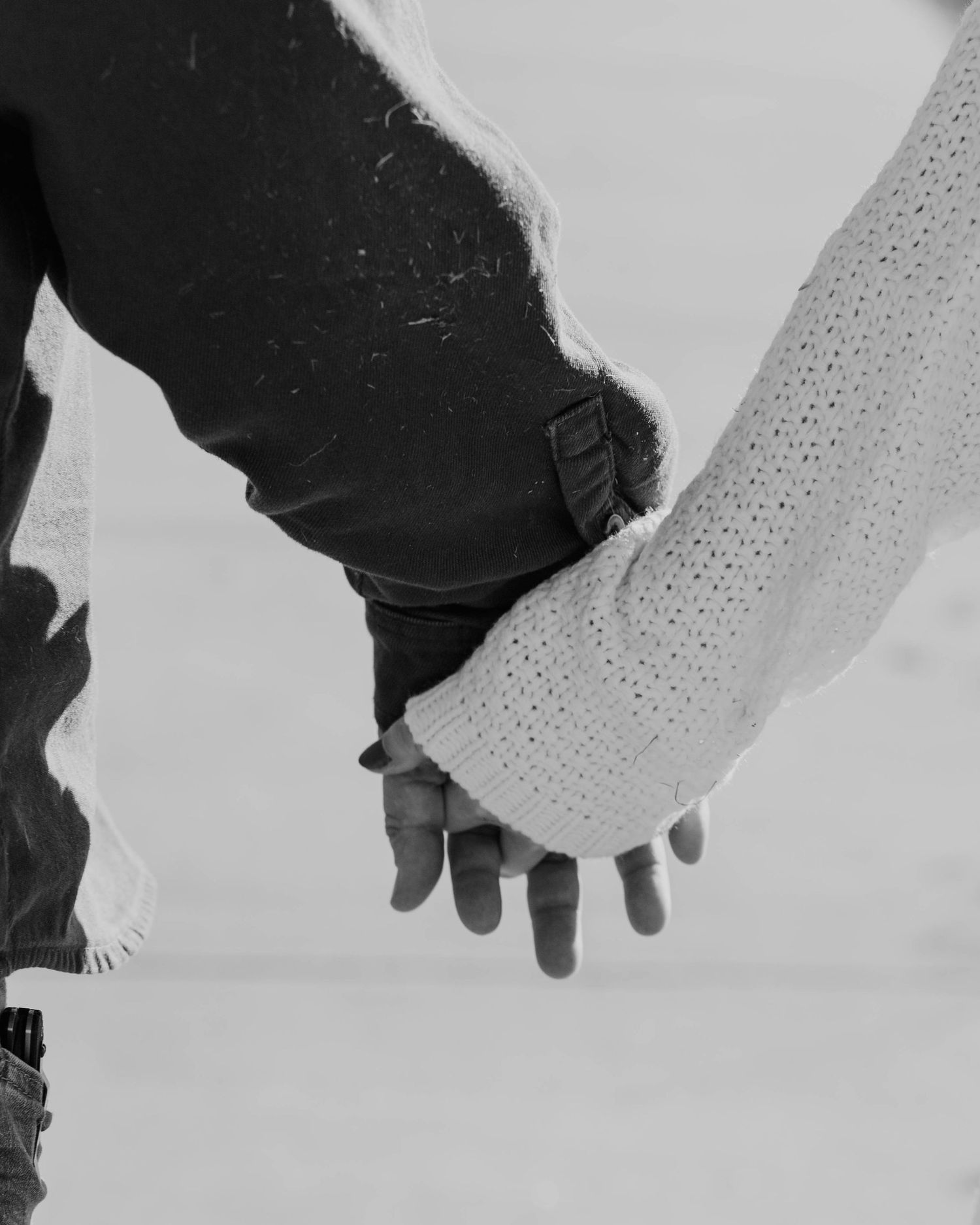 A black and white close-up photo of two people holding hands.