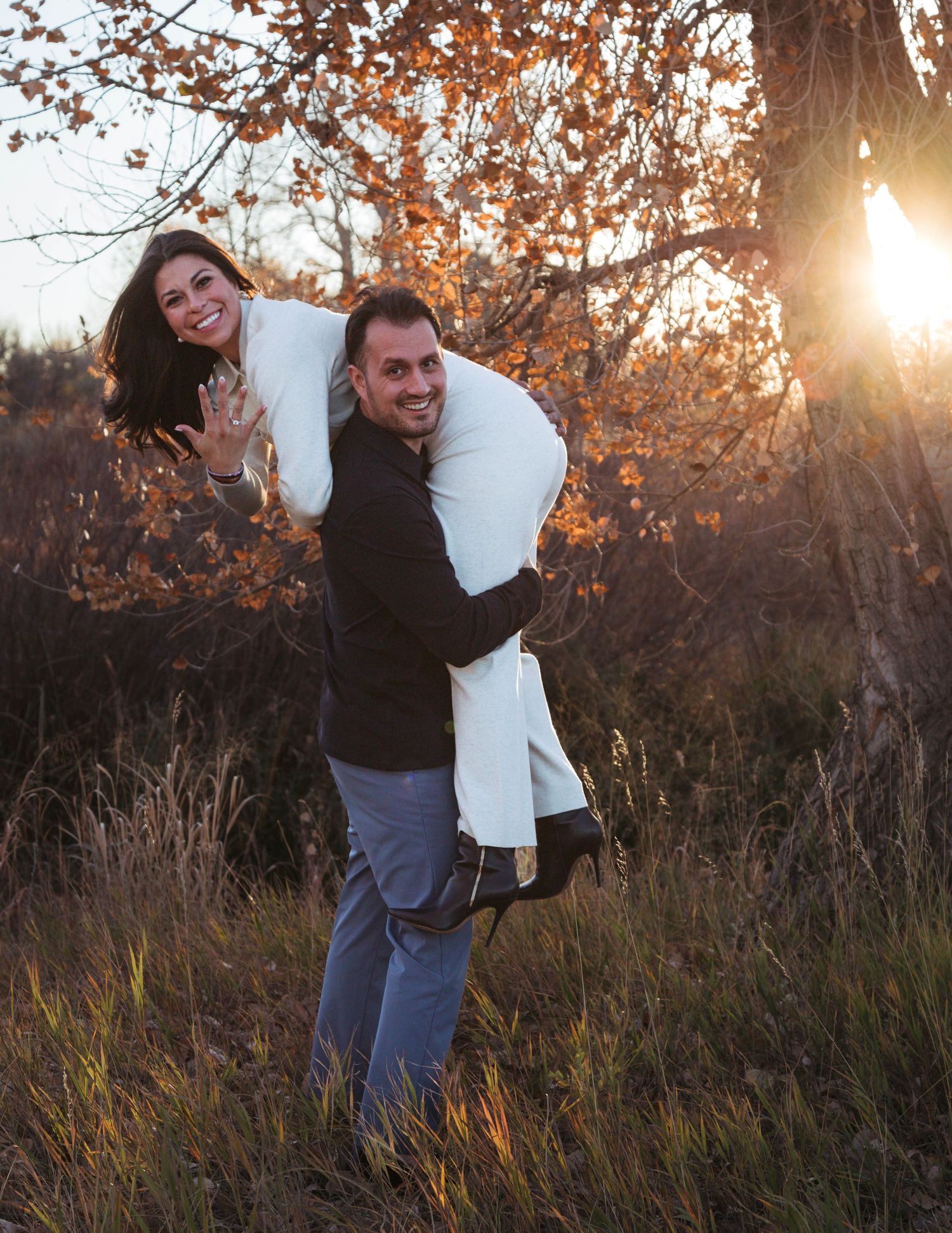 A playful autumn scene in tall grass with golden sunlight filtering through trees at sunset.