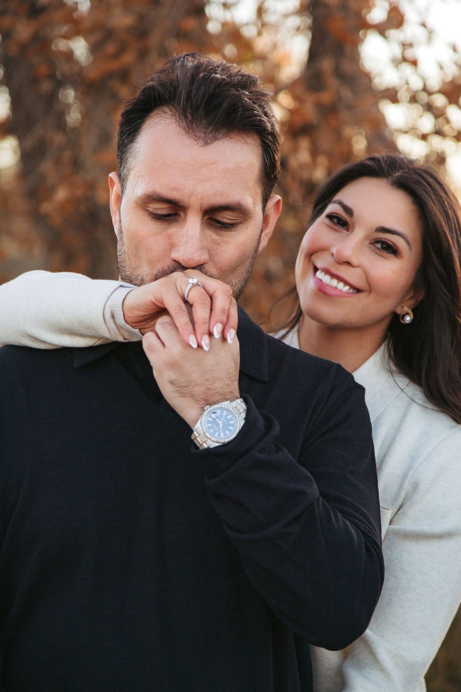 A romantic couple shares tender moments in a series of candid photos with autumn foliage in the background.