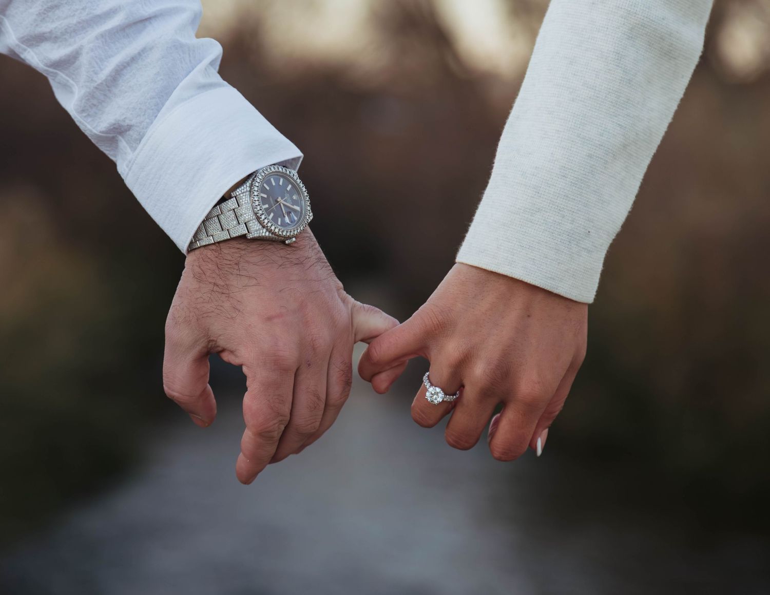 Close-up view of two hands with wedding rings touching fingers together in a romantic gesture.
