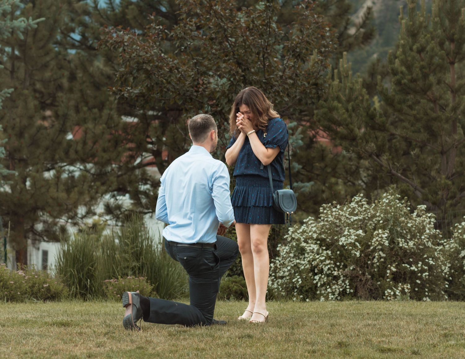 An emotional marriage proposal reaction captured in a scenic mountain location.