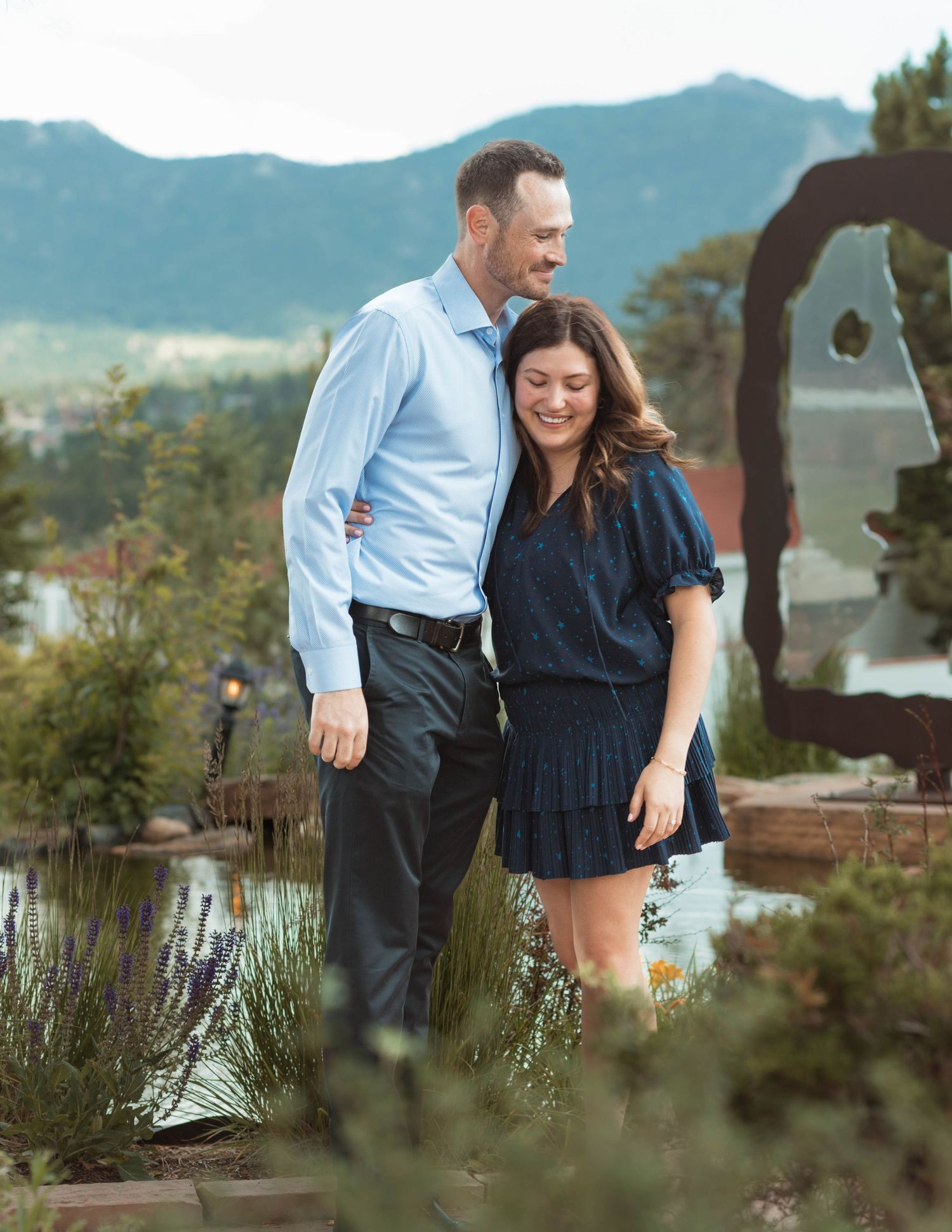 A couple sharing a tender moment in a mountain garden setting with natural scenery.