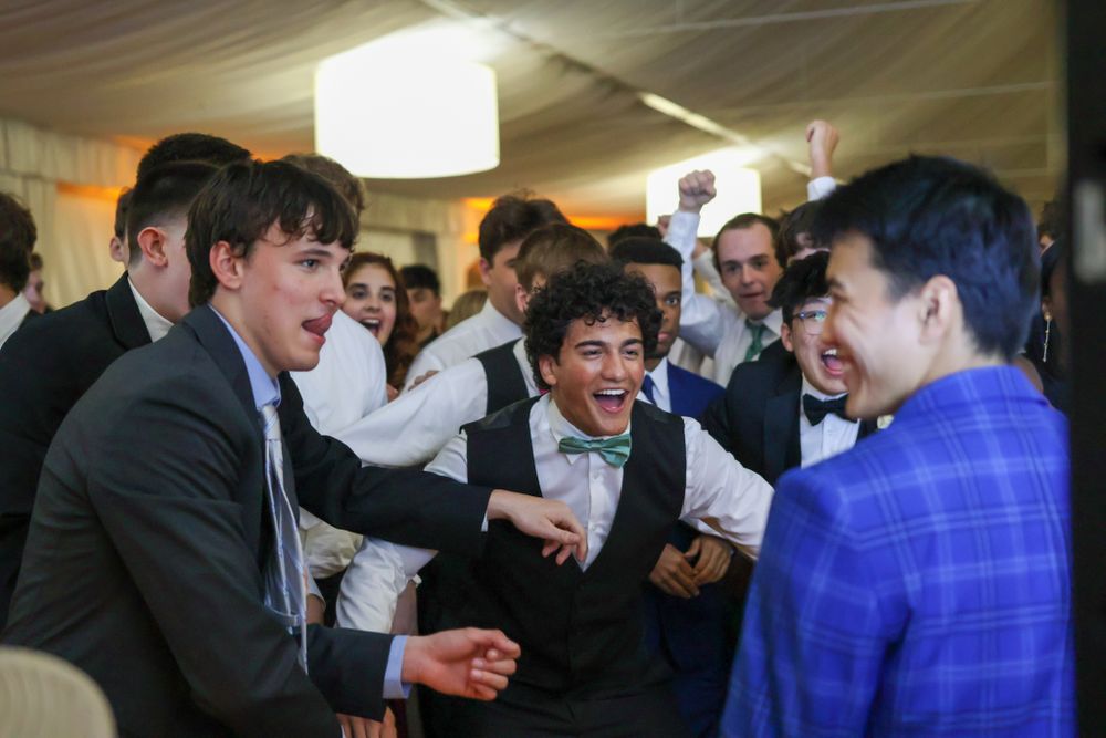 Group of formally dressed guests engaged in animated conversation at an indoor event.