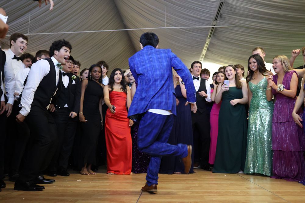 Dancer in bright blue suit performs in the center of a crowd at formal event.