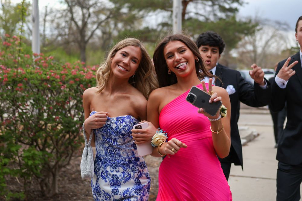 Two attendees in colorful dresses pose together during a formal event.
