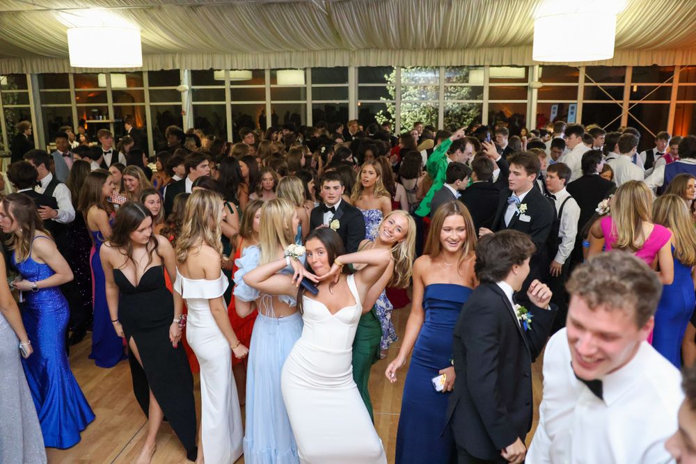 Large crowd of formal event attendees dancing and mingling on a dance floor under indoor lighting.