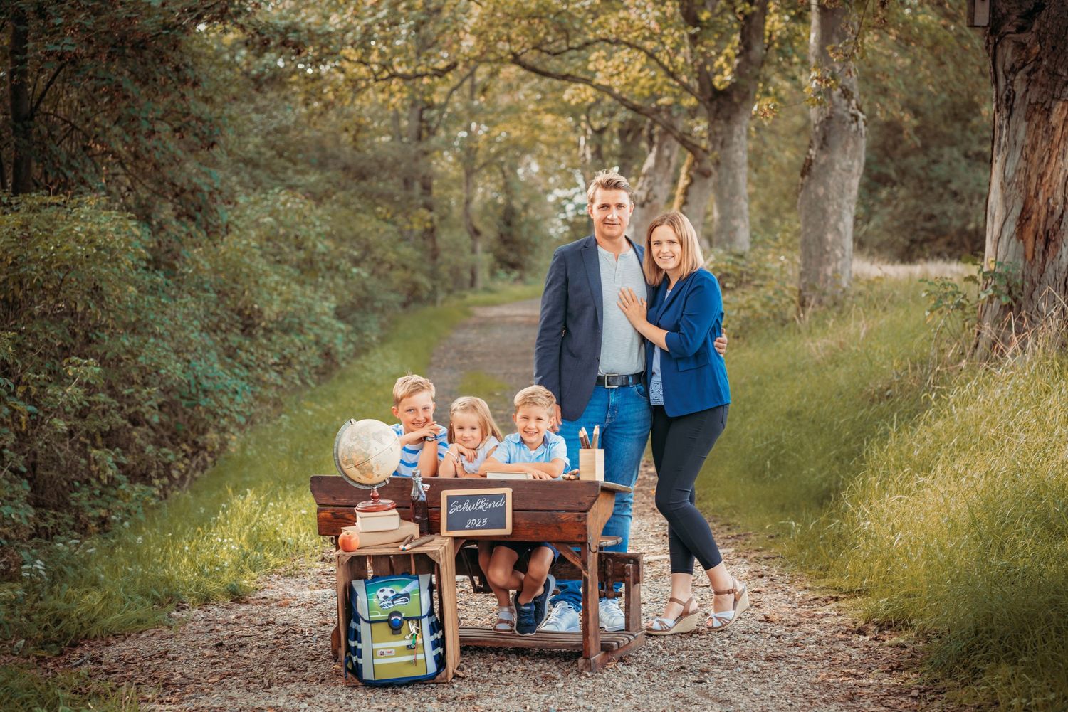 Family photo session with vintage desk setup on woodland path.