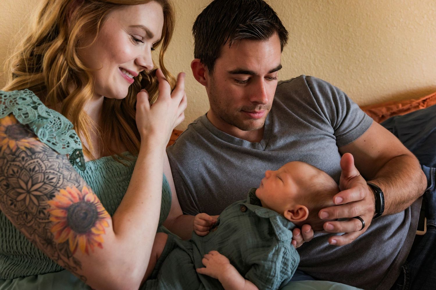 A family shares a tender moment together on the bed, with a small child and parents in casual attire.