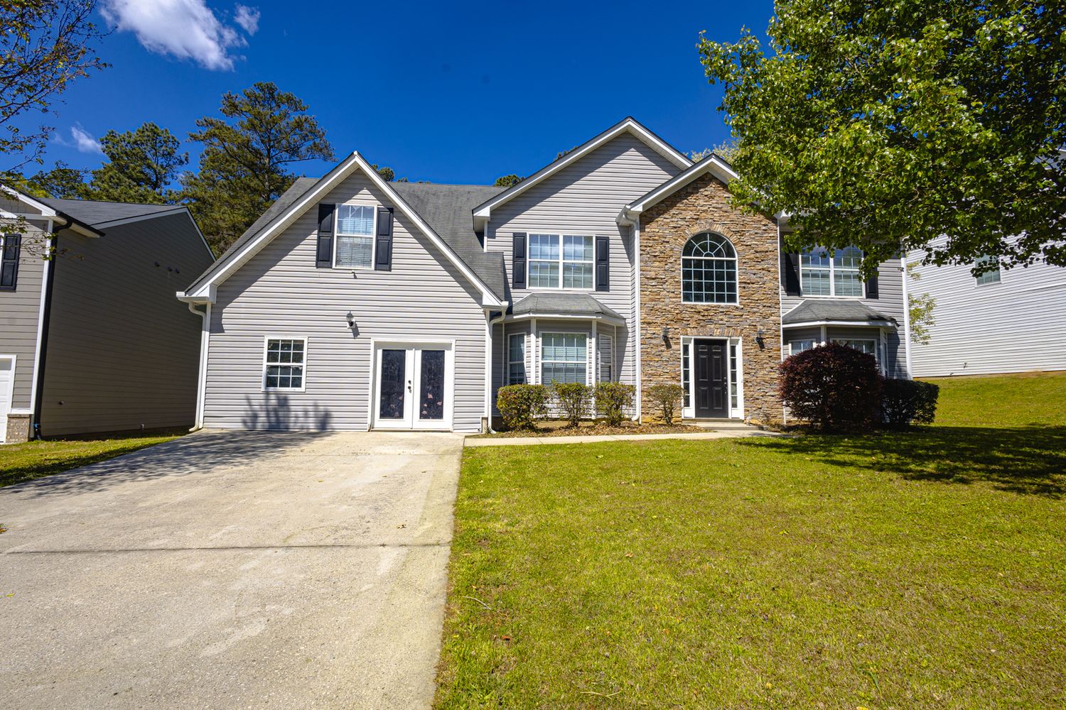 Row of suburban homes with green lawns under bright blue sky.