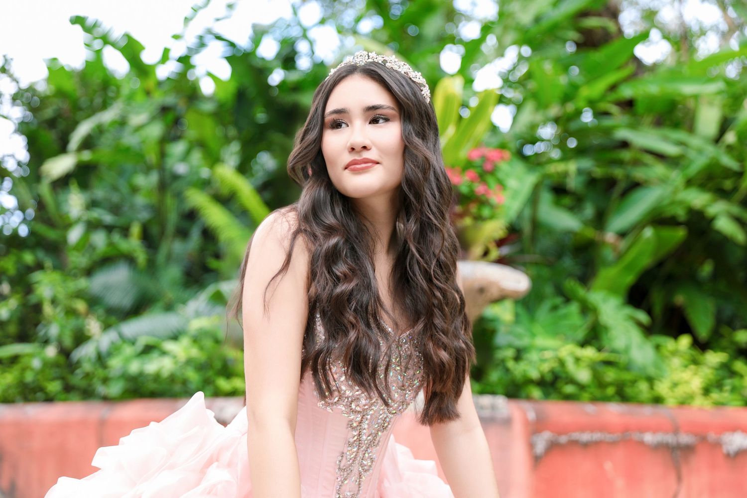 Soft pink beaded gown captured in lush tropical garden setting.