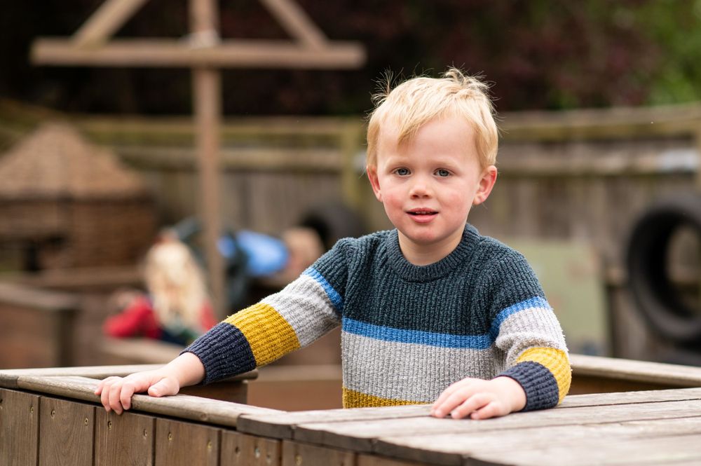 little boy on a climbing frame during a nursery photoshoot, in Ashtead, Surrey