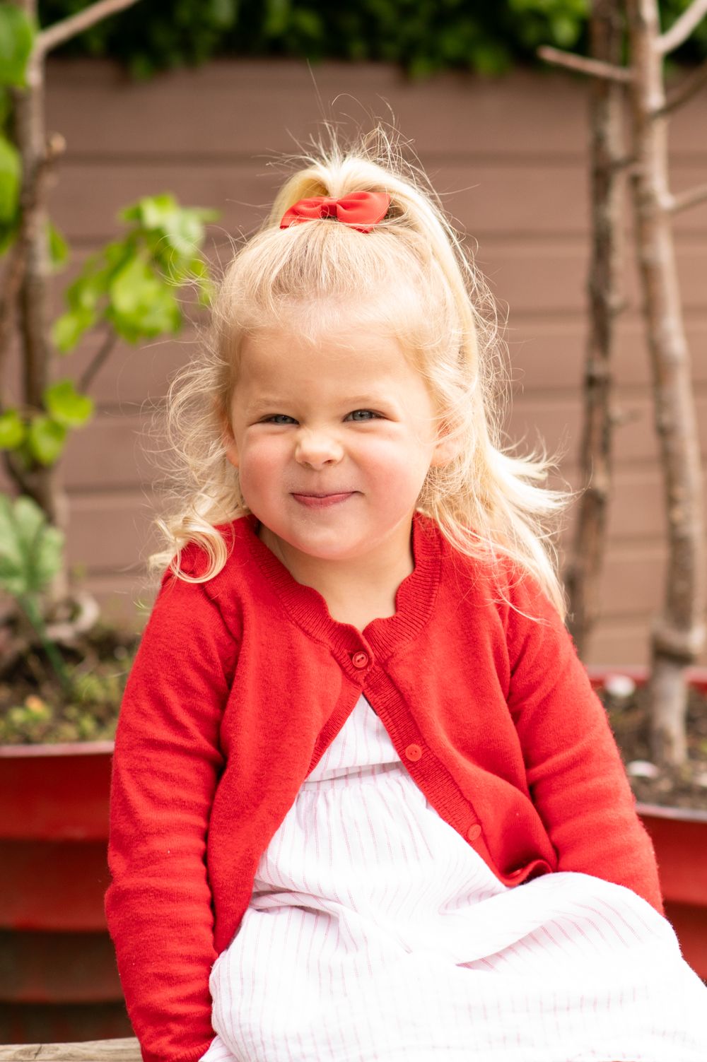 Young girl scrunching her nose up at the camera during nursery photoshoot, in Ashtead, Surrey