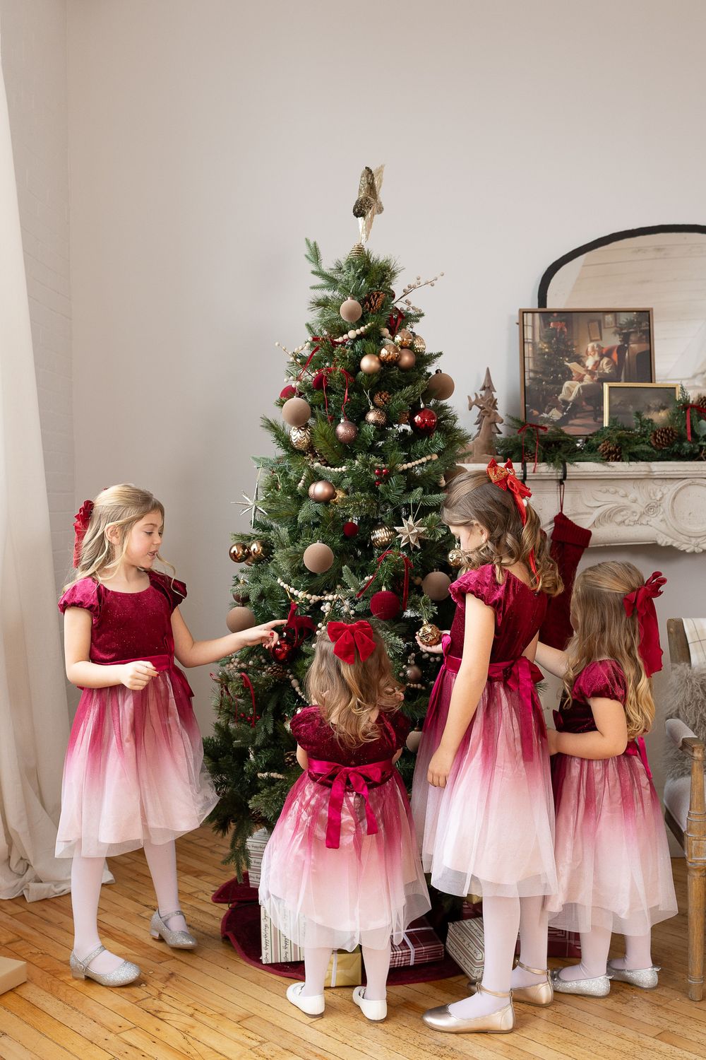 A sequence of children in red and pink dresses decorating a Christmas tree in a bright living room.