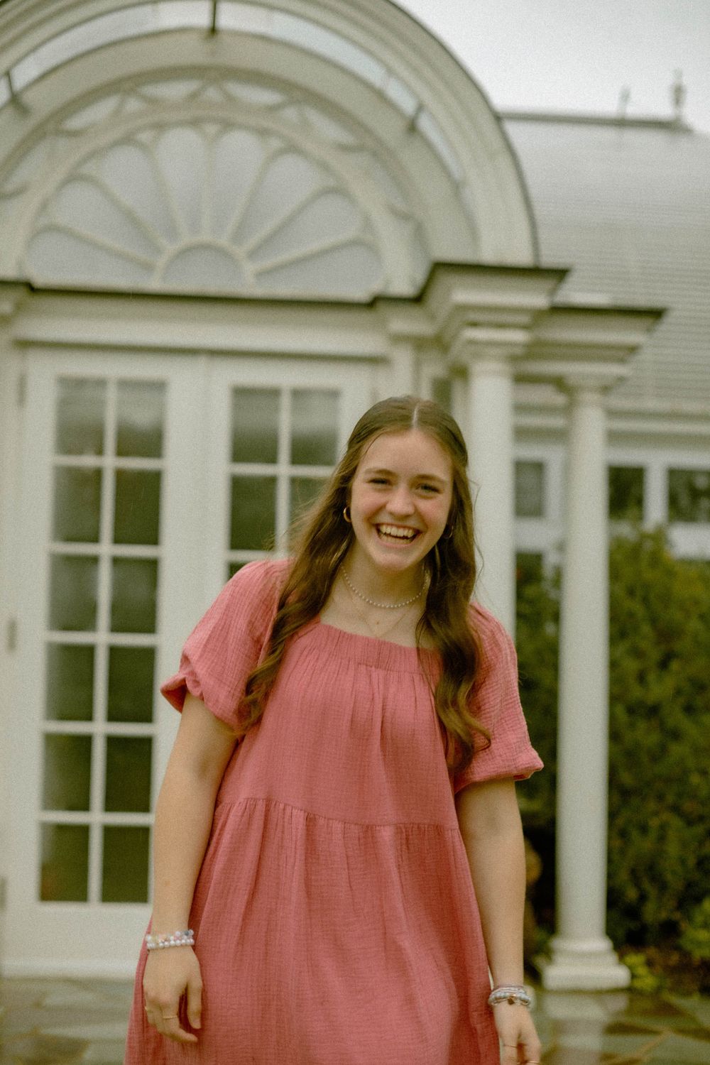 A candid portrait in front of elegant white architecture with decorative columns and windows.