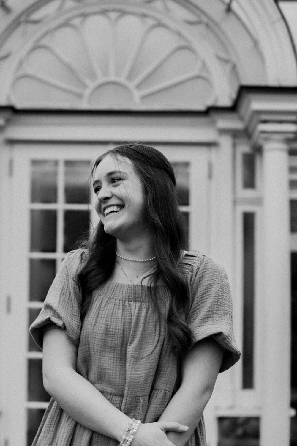 Black and white portrait showcasing genuine laughter against classical architectural details.