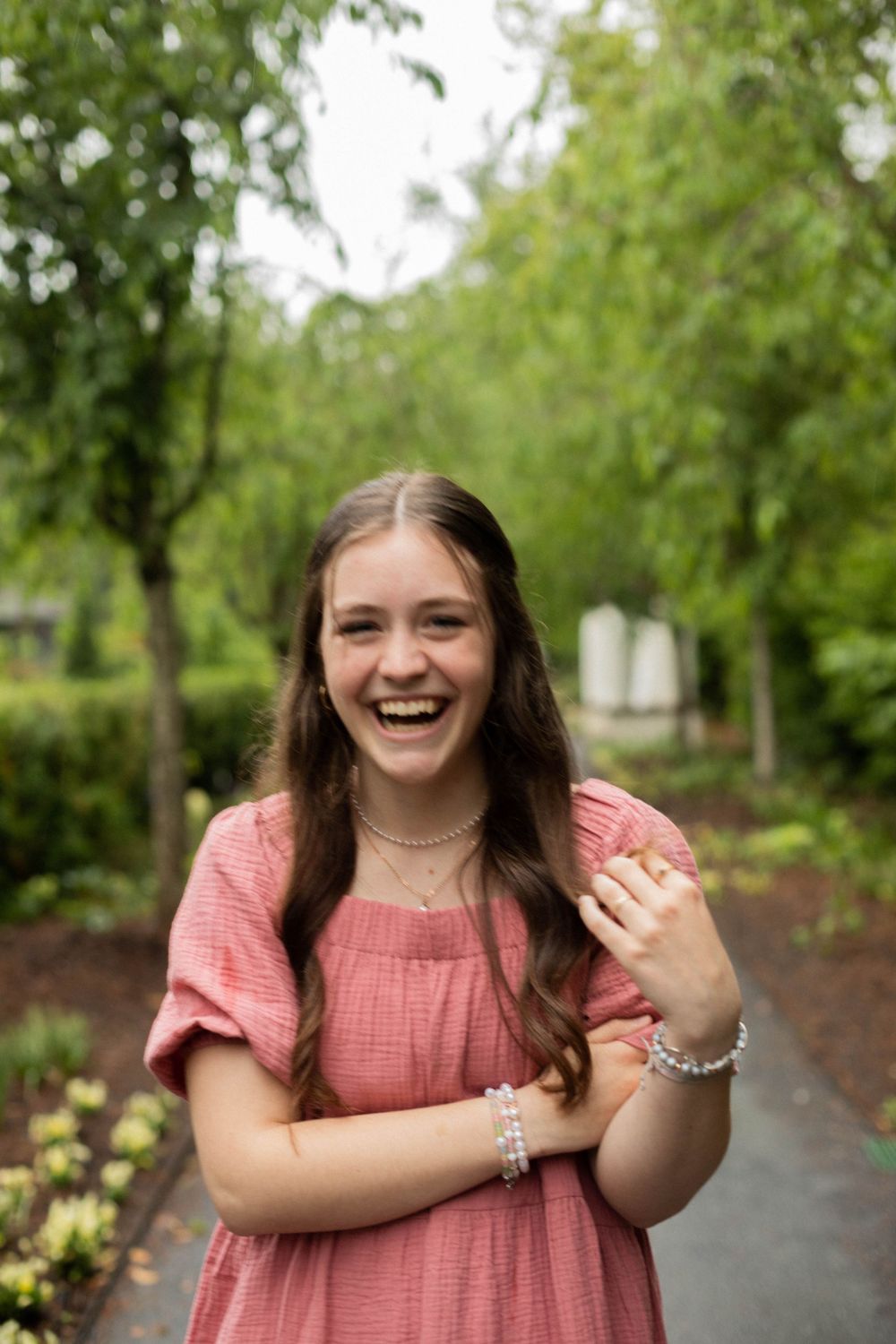 Candid laughter captured in a garden setting with blooming trees and pathway.