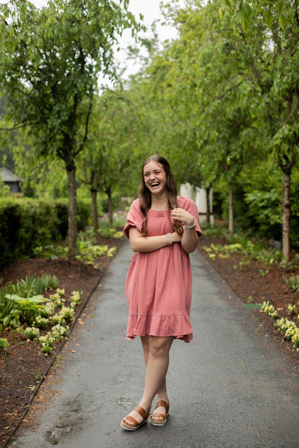 Carefree pose on garden path surrounded by weeping willow trees and landscaped grounds.
