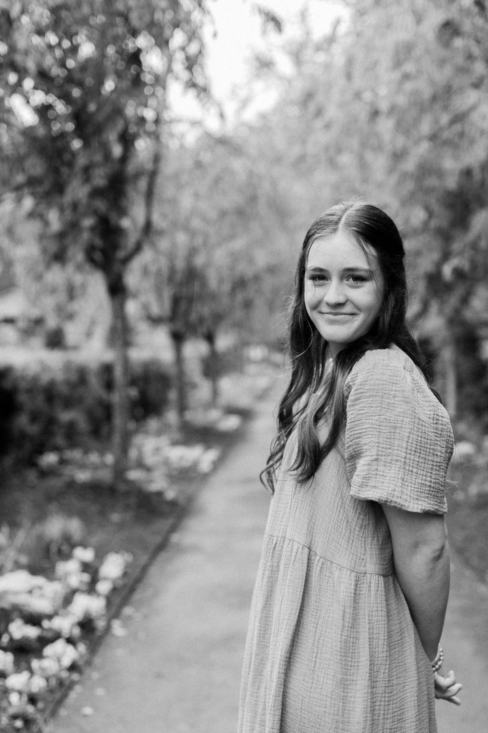 Black and white portrait on garden path with elegant landscaping and trees.