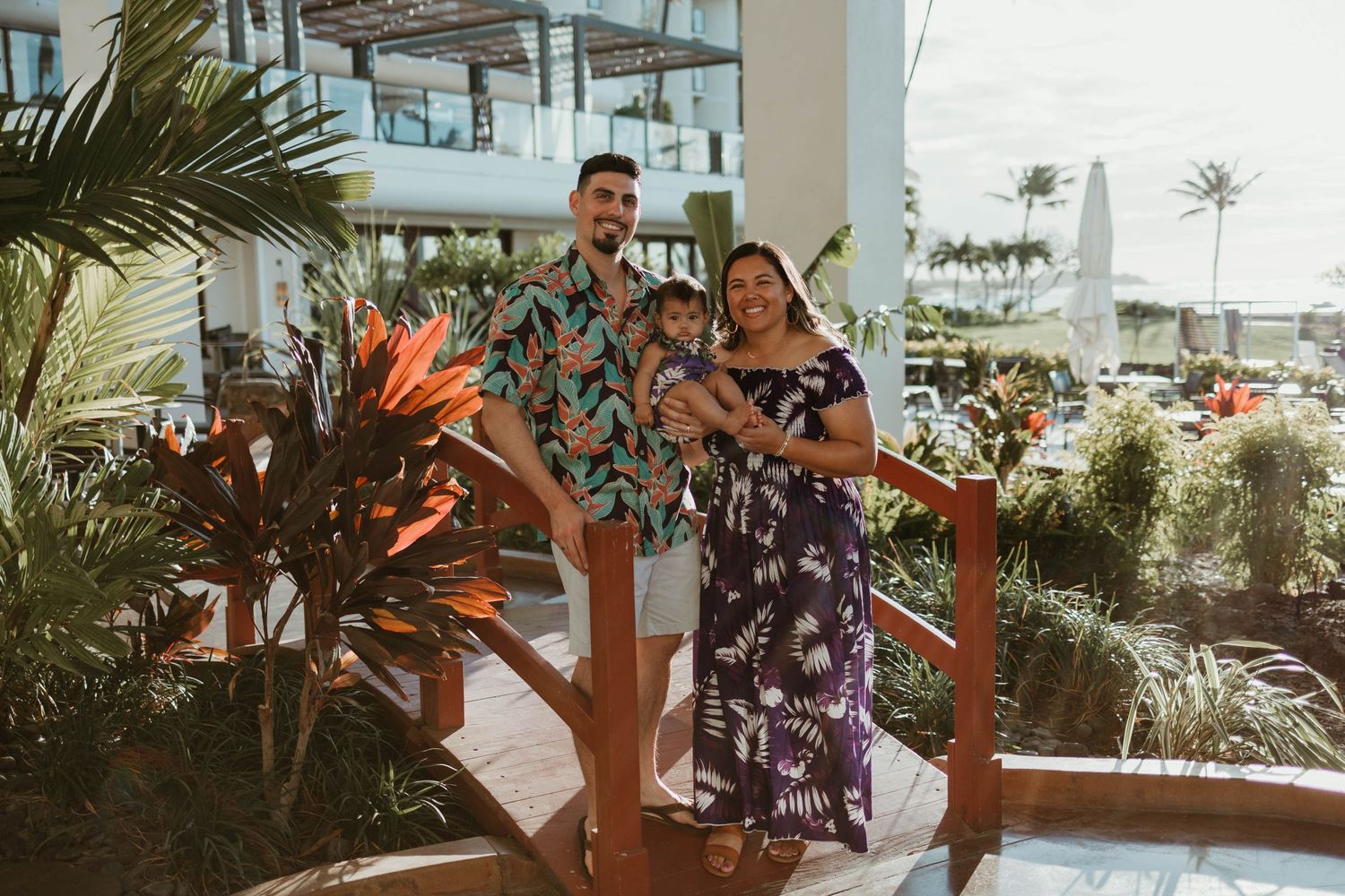 Couple standing on a tropical balcony surrounded by lush palm plants and tropical foliage.