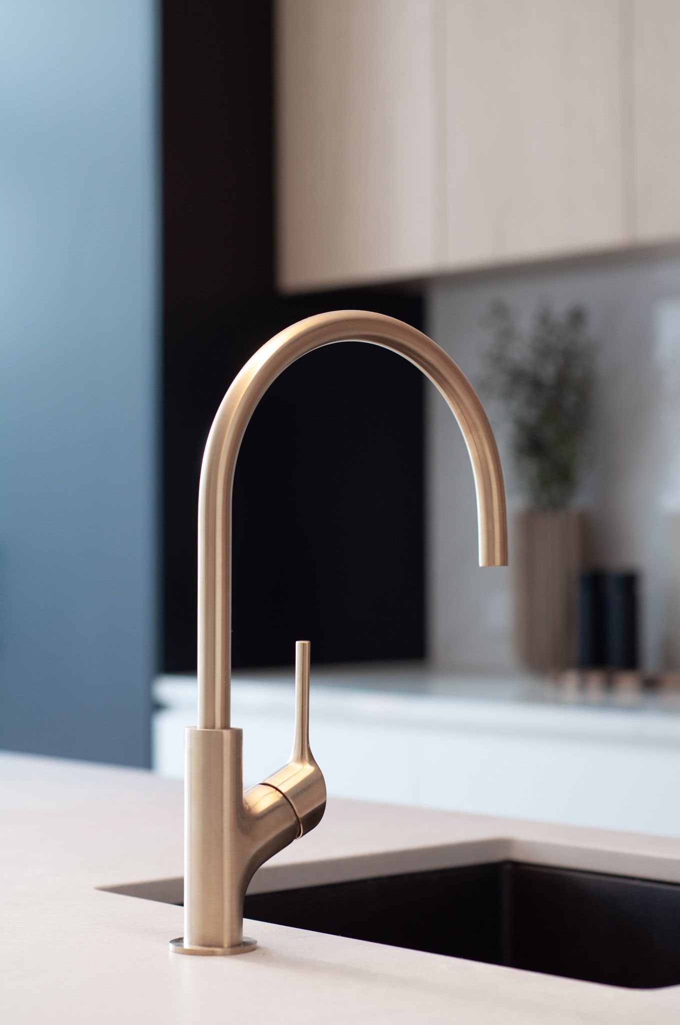 Sleek brushed gold kitchen faucet with minimalist design against white countertop.