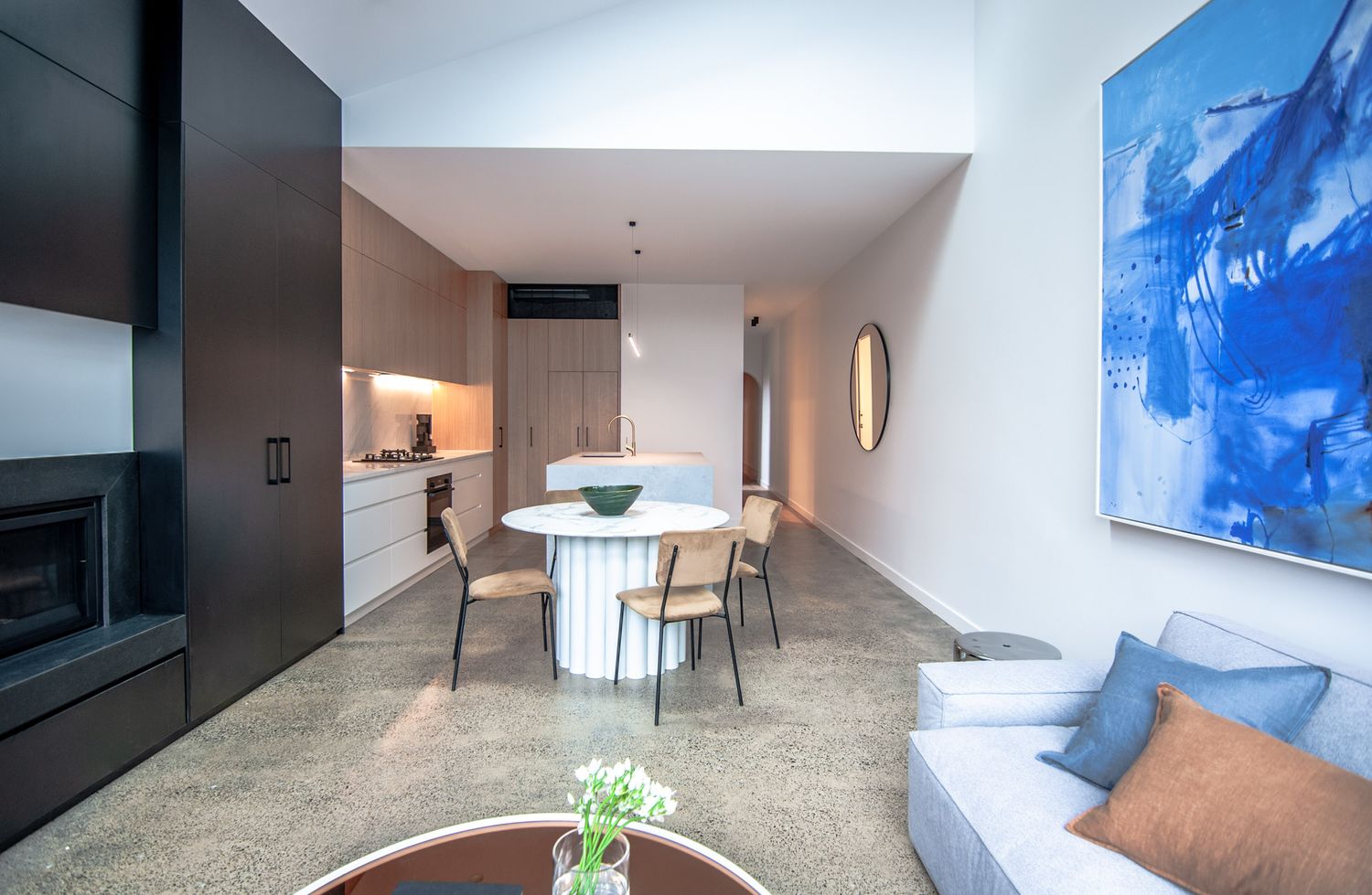 Modern open-plan living area with blue artwork and contemporary furnishings in neutral tones.