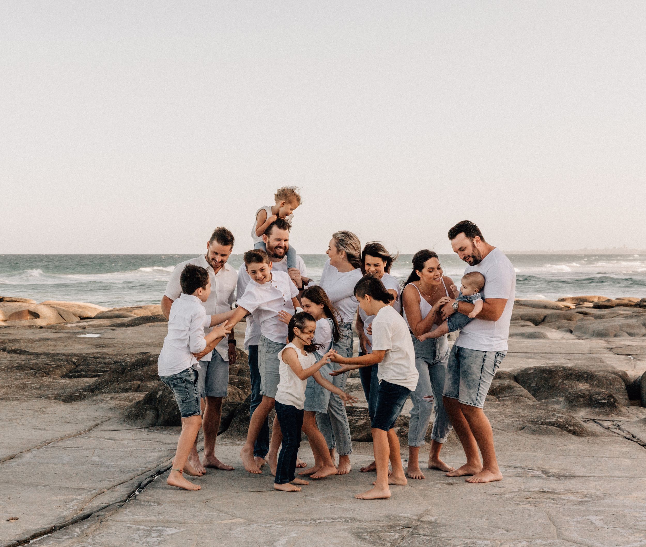 Group of friends gathered on rocky beach at sunset.