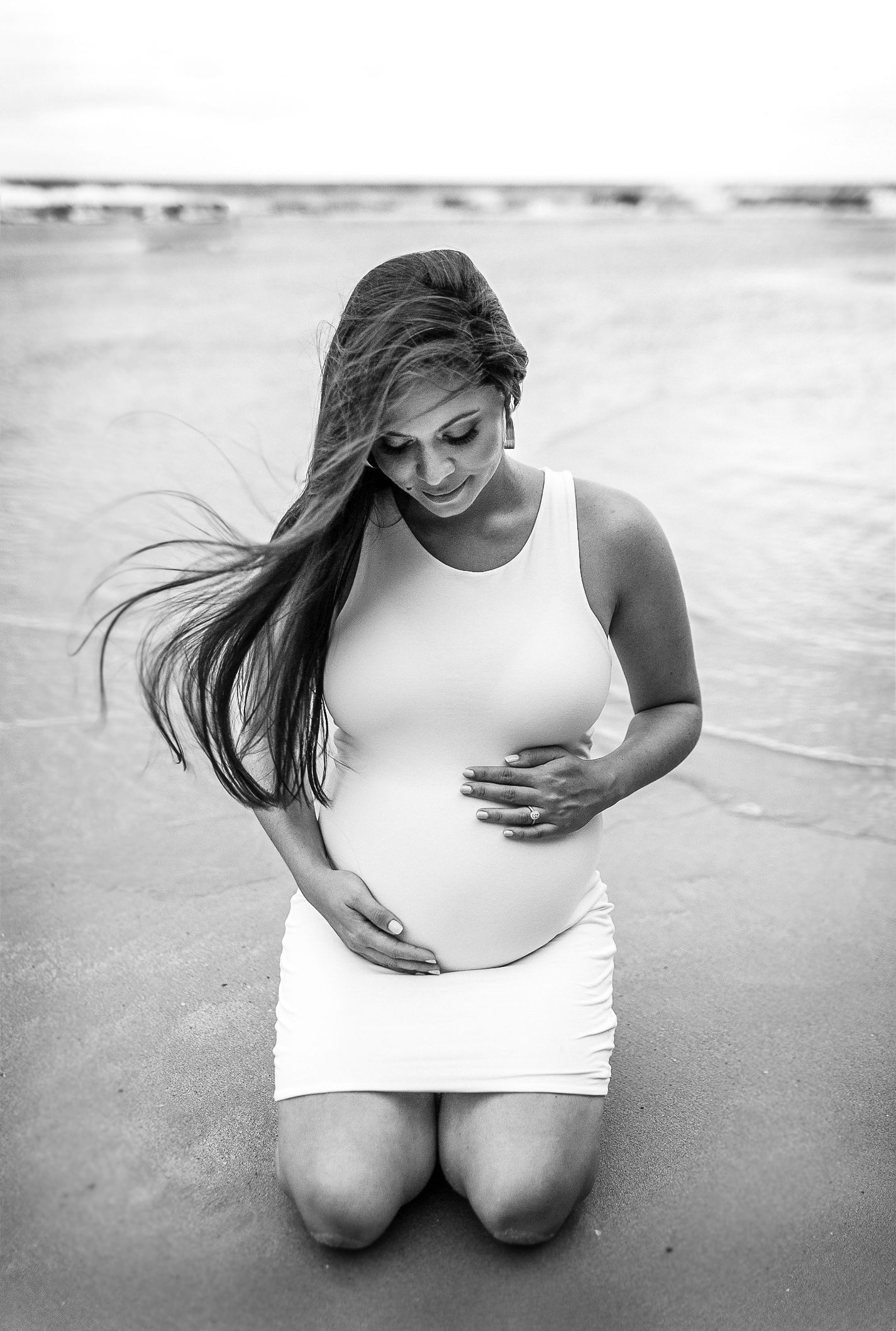 Black and white maternity portraits on a sandy beach.