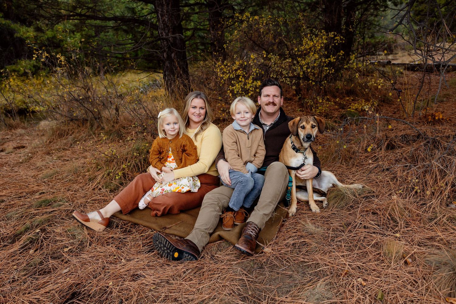 Casual outdoor family portrait with blue and denim clothing against autumn desert backdrop.