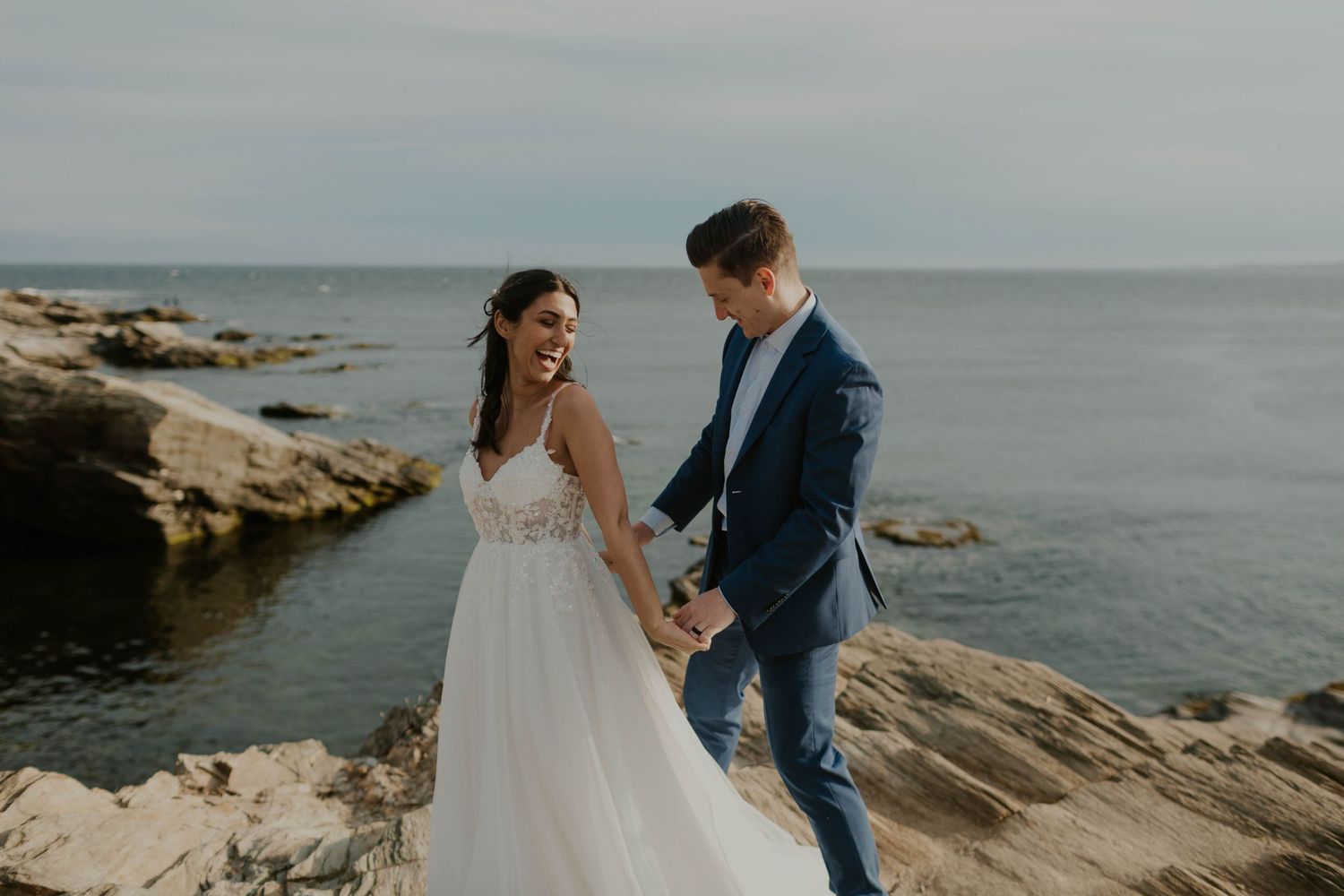 A romantic coastal wedding portrait on rocky cliffs overlooking the ocean.