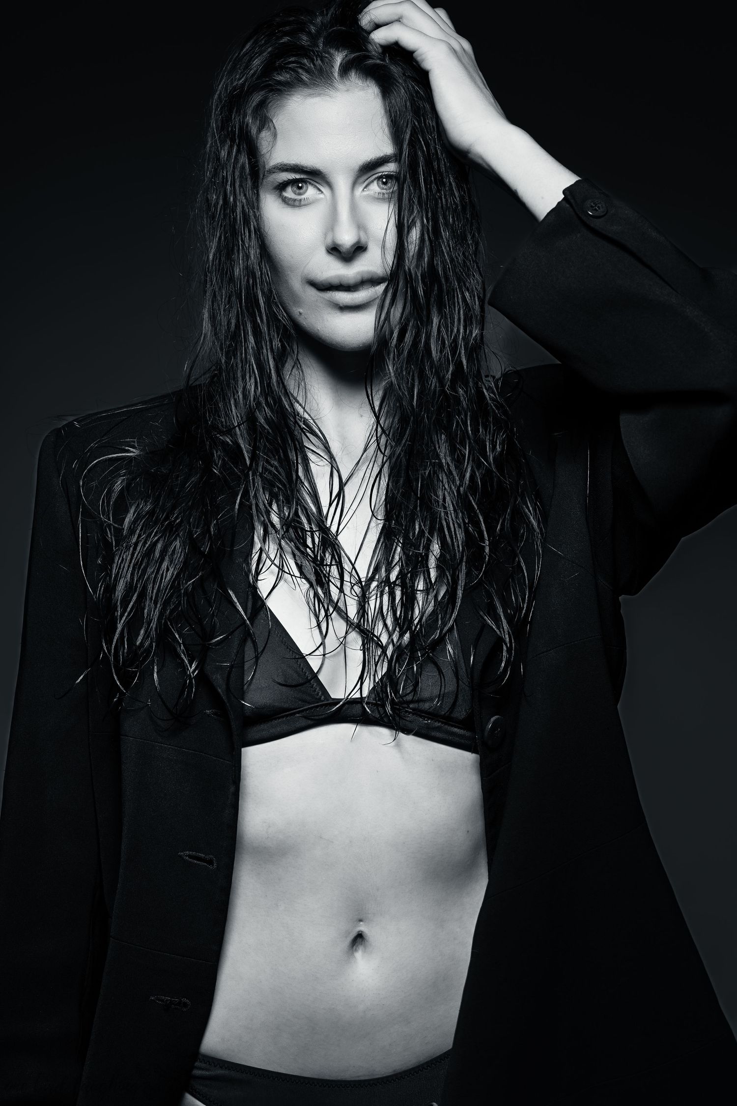 Black and white fashion portrait of a model with wet hair wearing a black blazer and bralette.