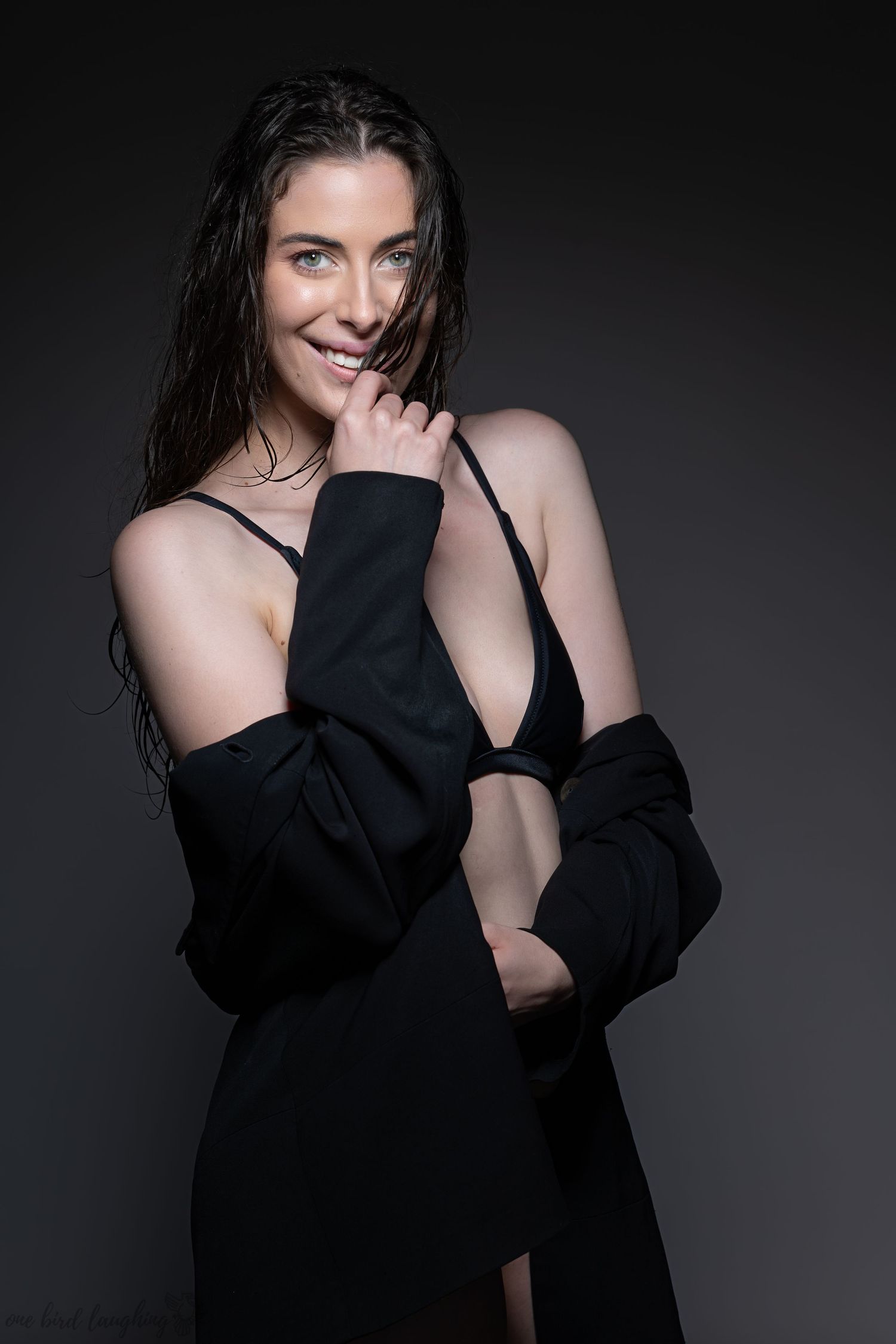 Artistic portrait of a model with wet hair wearing a black jacket against dark background.