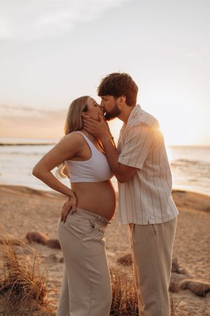 Romantic beach photoshoot of couple in neutral tones during golden hour.