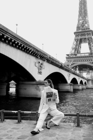 Fashion photoshoot by the Seine River with Eiffel Tower visible in background.