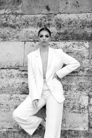 Fashion photography series featuring white blazer against textured stone wall background.
