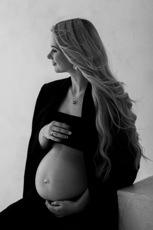 Dramatic black and white side profile maternity portrait with flowing hair.
