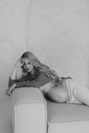 Artistic black and white maternity boudoir photo on light colored couch.