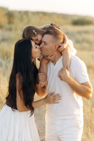 Romantic couple in white clothing sharing intimate moment in sunlit field.