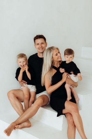 Family of four posing playfully against white backdrop in casual attire.