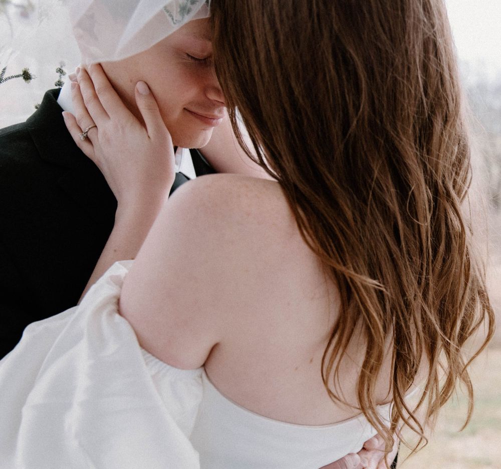 Intimate romantic moment between couple in white captured from behind.