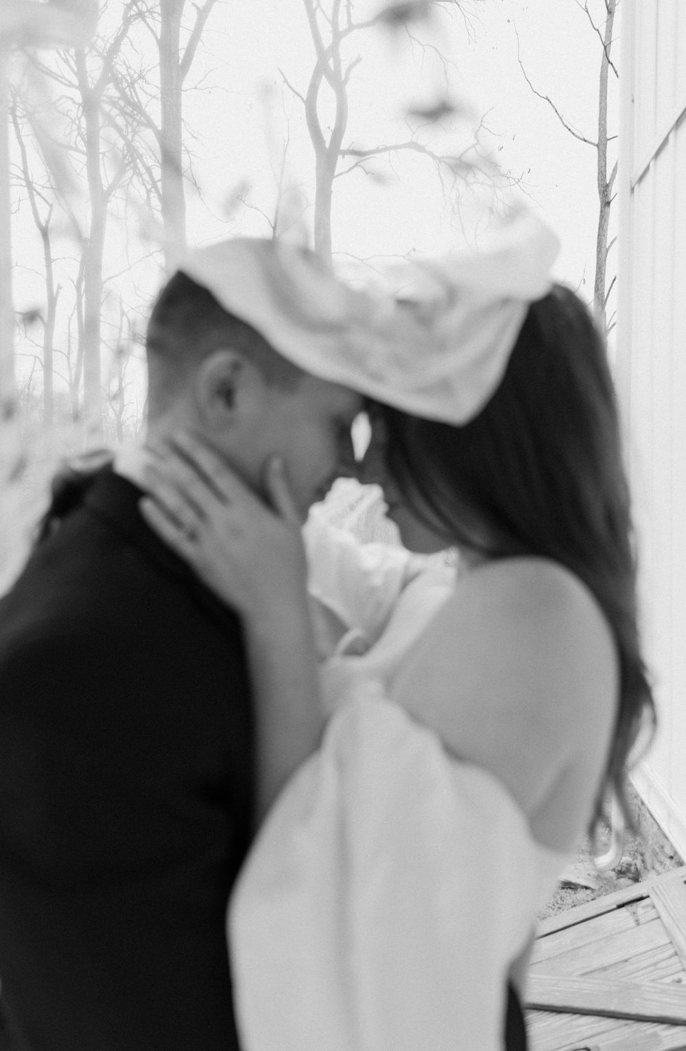 A romantic black and white photograph showing an intimate moment between two people outdoors.