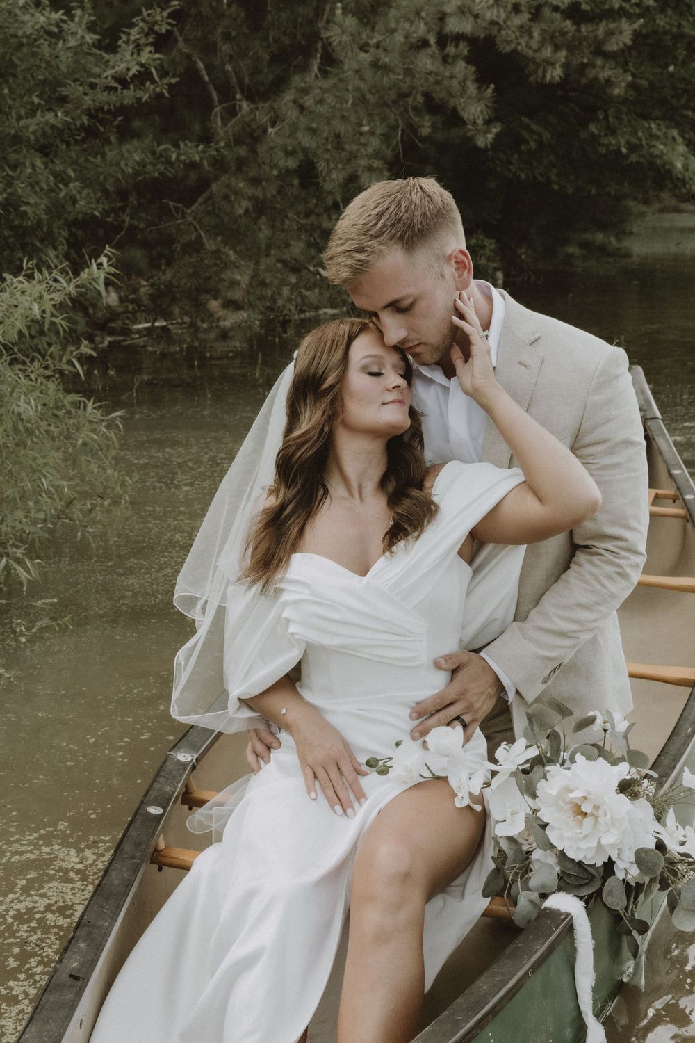 An intimate moment between newlyweds in a canoe decorated with white flowers.
