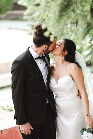 Intimate wedding moment captured under willow trees with soft natural lighting.