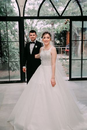 Elegant wedding portrait framed by arched window panes with garden view.