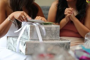 A group gathers around a table for a creative craft activity with silver boxes and decorative materials.