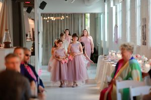 Bridesmaids in matching mauve dresses walking through an elegant hallway with natural light streaming in.