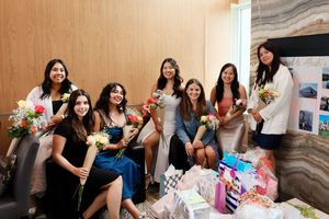 Several people sit together at a table working on decorative gift boxes during a social gathering.