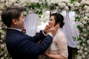 A tender moment between a couple at their elegant flower-adorned wedding ceremony with white roses and delicate drapery.