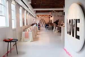 Modern industrial event space with white walls, exposed ceiling, and natural light streaming through windows.