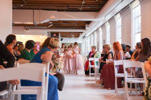 A large group mingles in a modern loft-style space with natural lighting and white walls.