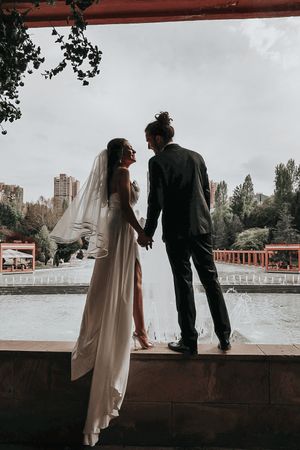Silhouetted wedding couple shares intimate moment on urban bridge overlook.